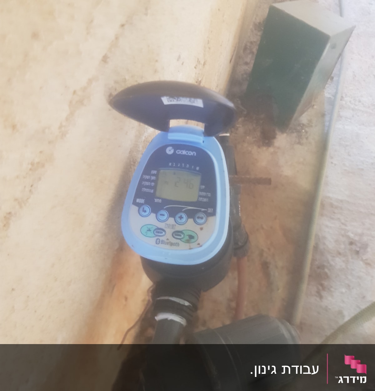 טיימר השקיה דיגיטלי מחובר לצינור בגינה
